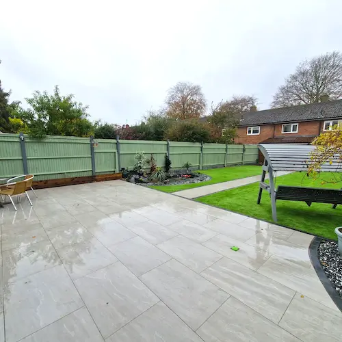 Photo of a green landscaped grass garden with stone patio